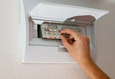 Ruka nastavuje jistič v rozvaděči pro elektroinstalaci.