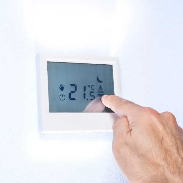 Ruka nastavuje teplotu na termostatu pro úsporu energie.