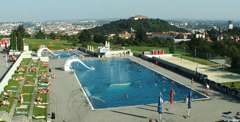 Venkovní bazén s vodními skluzavkami na kopci nad městem.