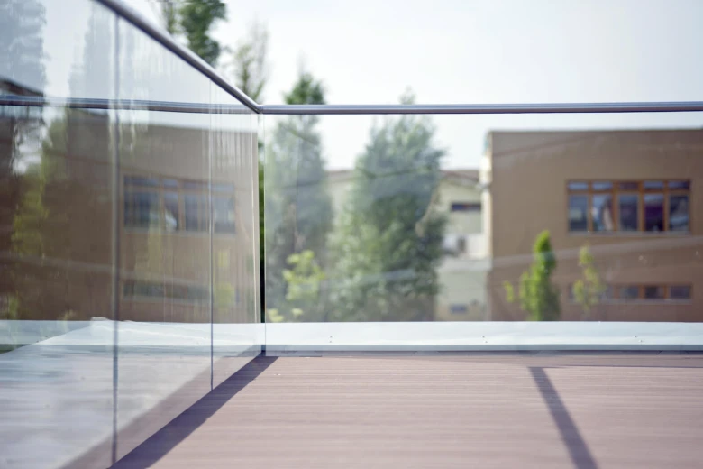 Moderní skleněné zábradlí na dřevěném balkóně s výhledem do okolí.