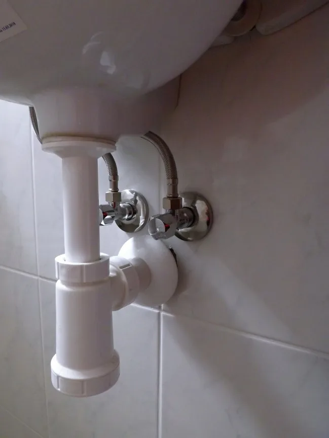 Podpultové umyvadlo s vývodem vody na dlažbě