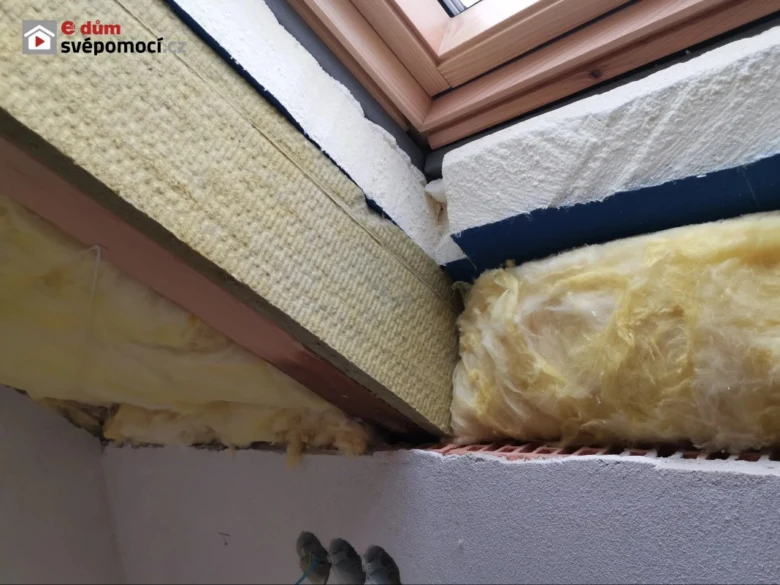 Detailní pohled na izolaci okna s minerální vlnou mezi trámy.