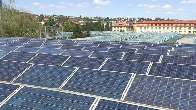 Fotovoltaické panely na střeše budovy v městském prostředí.