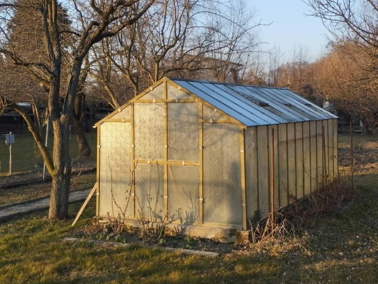Dřevěný skleník s průsvitnými panely na trávníku.