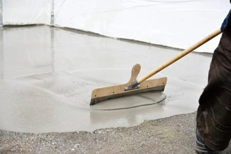 Pracovník vyrovnává samonivelační beton dřevěným hladítkem.