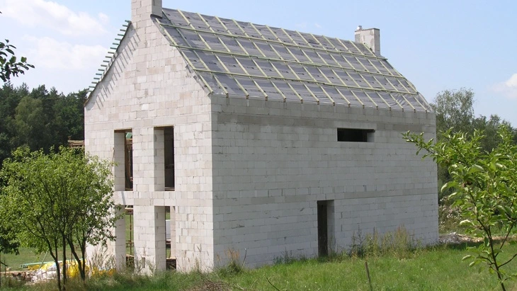 Dům z porobetonu ve stavbě s fotovoltaickými panely na střeše.