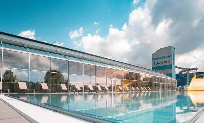 Vnitřní bazén v Aquacentru Šumperk s lehátky a skluzavkami.