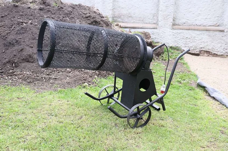 Černé síto na kolech pro prosévání zeminy v zahradě.