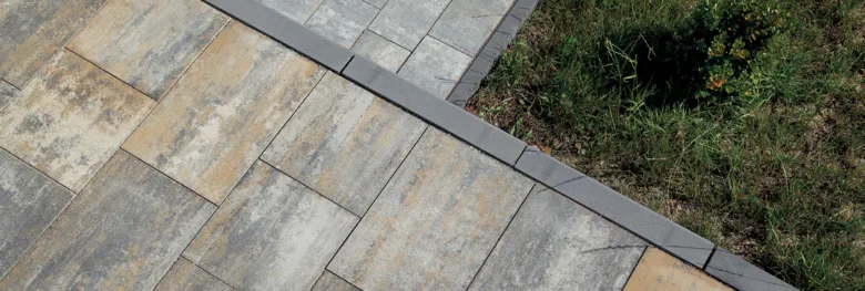Nově položený betonový obrubník oddělující dlažbu od trávníku.