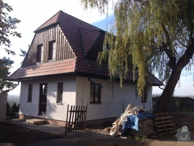 Starý dům v rekonstrukci s materiály na zahradě a stromem.