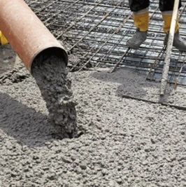Čerstvý beton se nalévá na ocelovou výztuž pro stavbu.