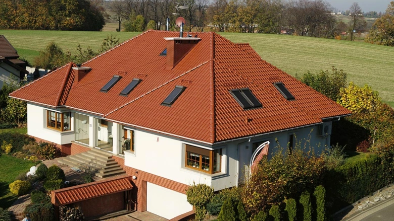 Moderní dům s polovalbovou střechou na venkově.
