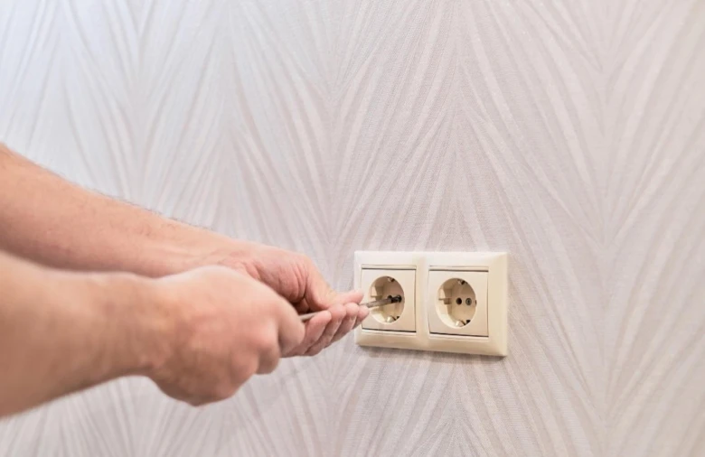 Ruční instalace elektrické zásuvky šroubovákem na stěnu.
