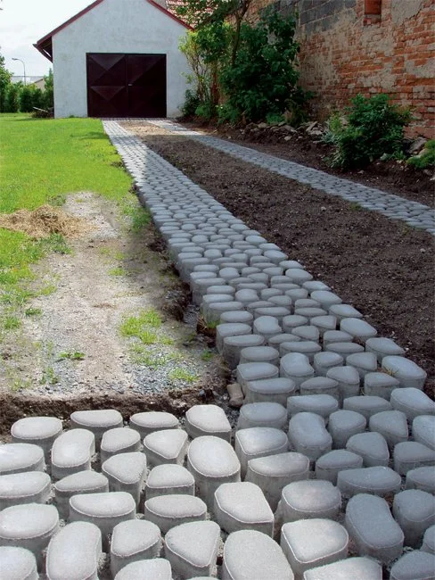 Nová cesta z propustných dlaždic vedle trávníku.
