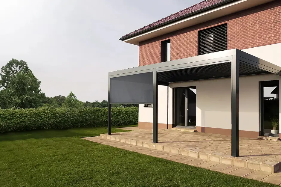 Bioklimatická pergola připojená k domu s rozklápěcími stínicími panely.