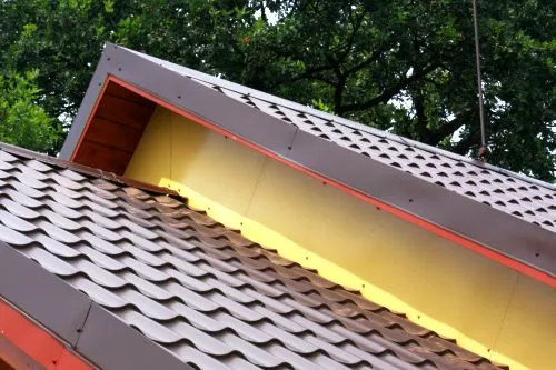 Detail bočního lemování střechy s plechy a izolací.