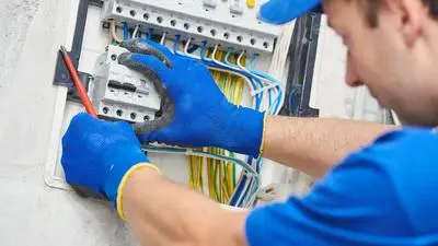 Elektrikář zapojuje vodiče do rozvaděče.