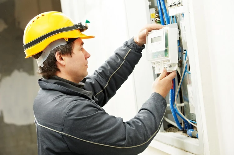 Elektrikář zapojuje rozvaděč s viditelnými kabely.