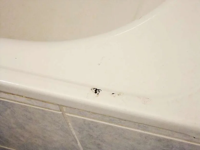 Poškozená smalta vany s černými skvrnami připravená k opravě tekutým smaltu.