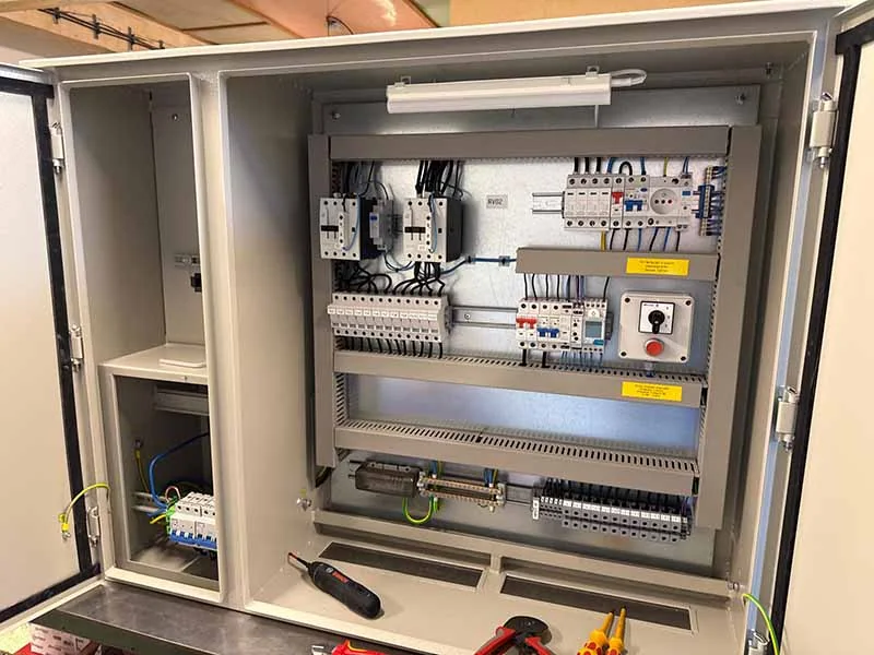 Otevřený průmyslový rozvaděč s elektrickými komponenty a kabeláží.