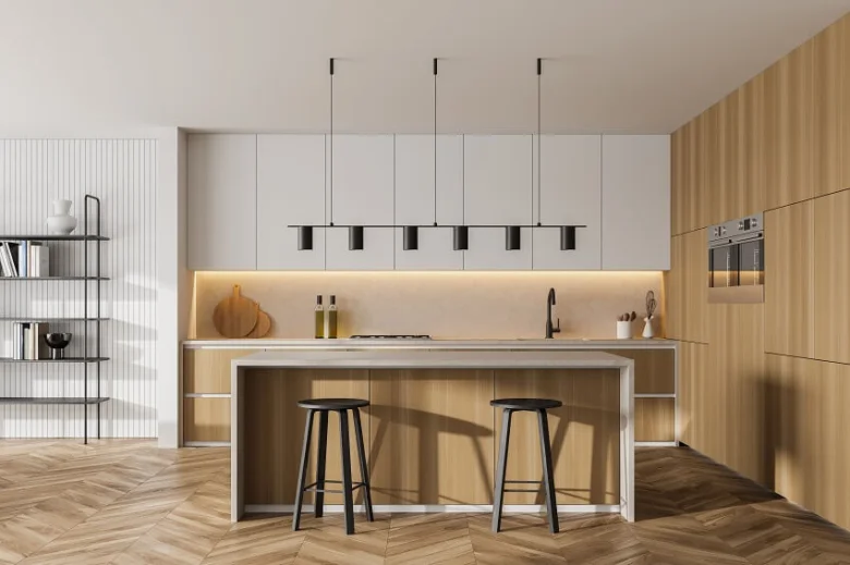 Moderní kuchyně s podskříňovým osvětlením a visutými lampami nad ostrůvkem.
