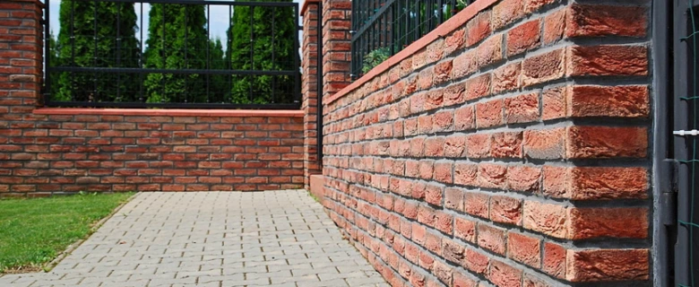 Červená cihlová zeď s dlažbou vedle ní ukazuje použití obkladu.