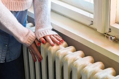 Ručník dotýká se starého radiátoru v bytě.
