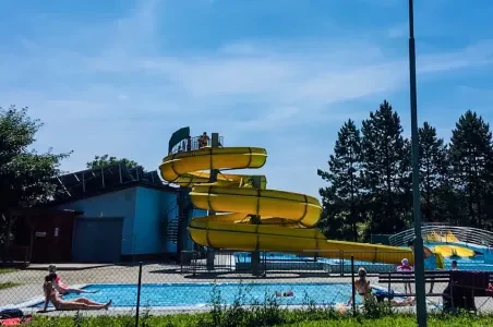 Žluté vodní skluzavky v bazénu s lidmi u vody.