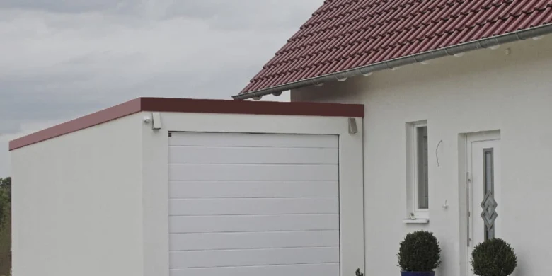 Bílá garáž přistavěná k domu s červenou střechou.