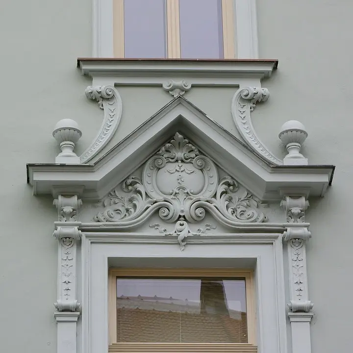 Detail zdobené římsy nad oknem na fasádě budovy.
