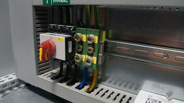 Otevřená elektrická rozvaděč s jističi a propojenými vodiči.