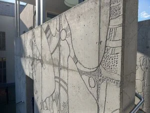 Detail fasády se sgrafitovou technikou na betonu.