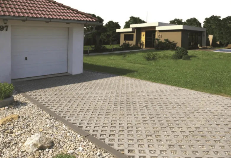 Zatravňovací dlaždice s kamínky na příjezdové cestě u garáže.