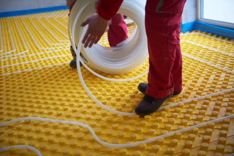 Instalace podlahového topení s rozvinutím hadice na žluté desky.