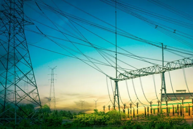 Vysokonapěťové vedení a elektrické věže na pozadí zapadajícího slunce.