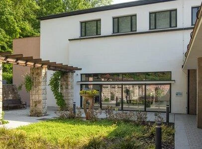 Moderní dům s hladkou bílou fasádou v zahradním prostředí.