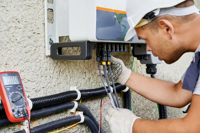 Elektrikář měří napětí v rozvaděči pomocí multimetru.