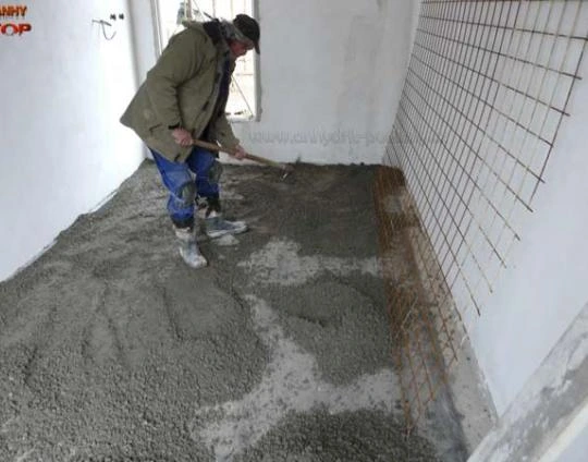 Muž nalévá betonovou podlahu s výztuhou pro topení.