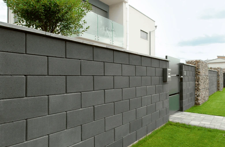 Moderní tmavě šedý betonový plot z prefabrikovaných bloků.