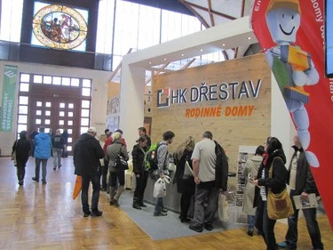 Stánek dřevostavby na výstavě s lidmi prohlížejícími materiály.