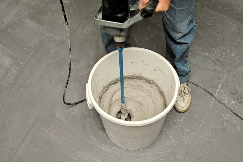 Smíchání sádrové omítky v kbelíku pomocí elektrického míchače.