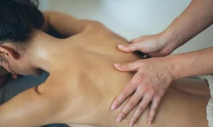 Masáž zad v sauně nebo wellness centru pro relaxaci.