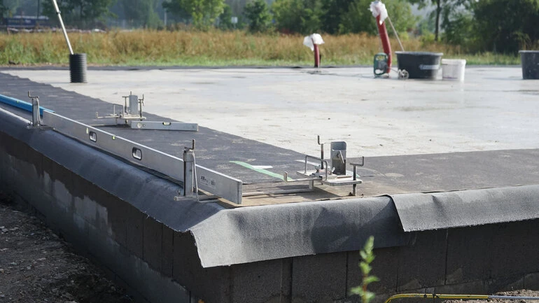 Příprava betonové podlahy pro stavbu rodinného domu s použitím úrovně.