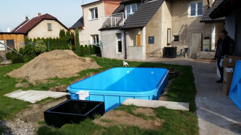 Modrý nadzemní bazén se instaluje v zahradě vedle filtrace.
