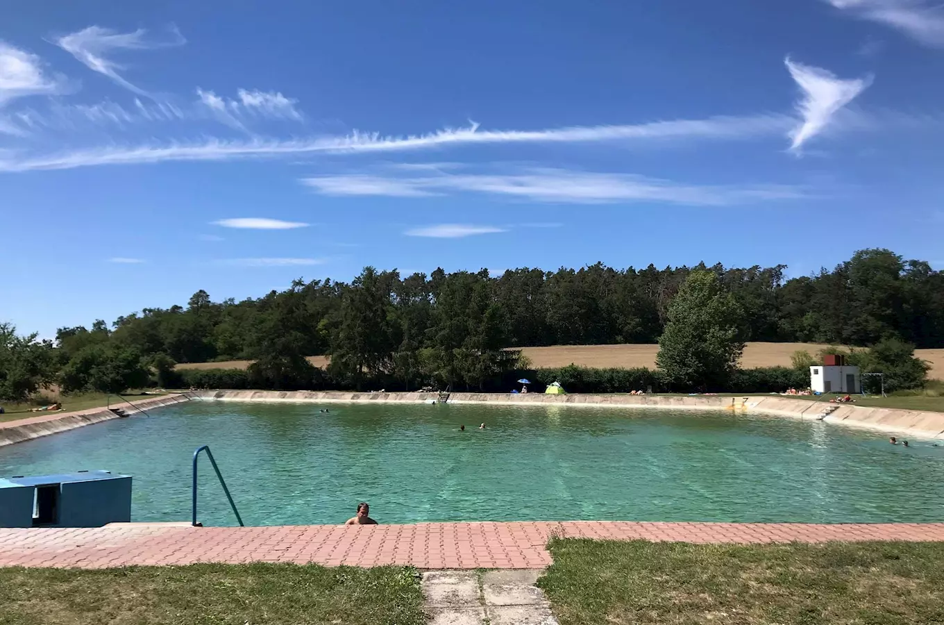 Venkovní plavecký bazén ve Všejanech s koupajícími se lidmi.