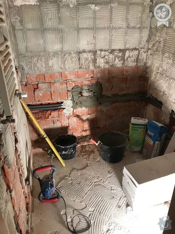 Koupelna v rekonstrukci s omítkou na podlaze a zdivem.