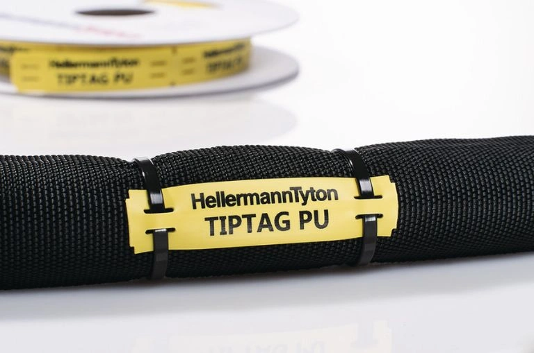 Žlutý popisovací štítek na černém kabelu značky HellermannTyton.