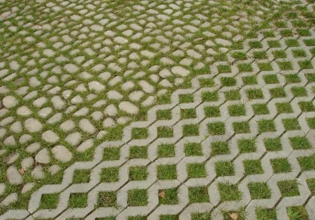 Zatravňovací dlaždice s rostoucí trávou vedle kamenů.