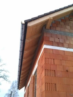 Detail dřevěné římsy na domě s okapem.