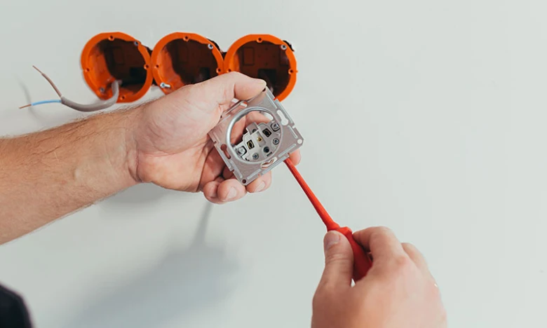 Instalace elektrické zásuvky do zdi s viditelným zapojením.